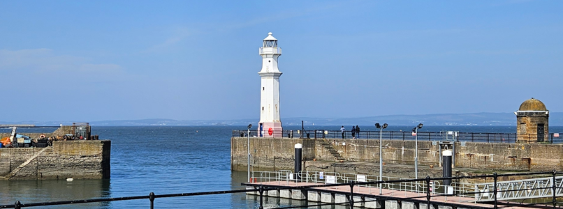 Newhaven Harbour with a blue sky in the background. The lighthouse stands out in the centre of the photo.