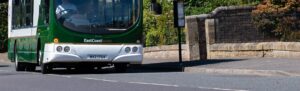 Image shows the front bumper of an East Coast bus beside a bus stop.